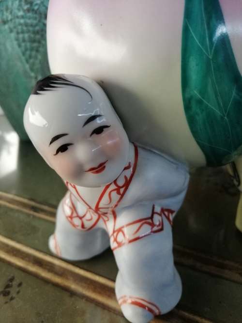 TWO CHINESE PORCELIAN STATUETTES CHILDREN CARRYING A RIPE PEACH