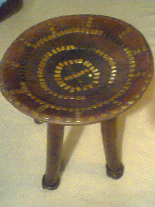 A Ethnic 4 Leg Stool from Gana with Brass & Copper inlay & Steel Rings on the 4 Legs.It's Heavy Teak