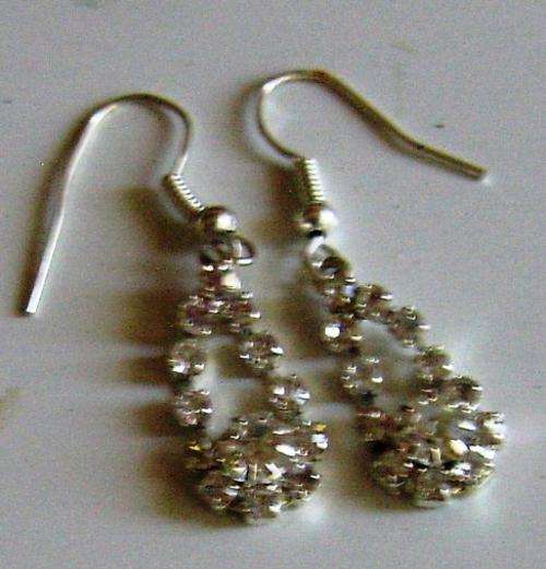 Silver coloured earrings with white stones.
