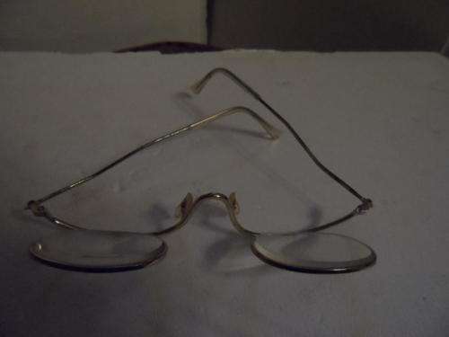 Pair of old spectacles with hinged lenses.
