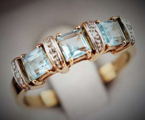 BLUE TOPAZ AND DIAMOND TRILOGY 9ct YELLOW GOLD RING.
