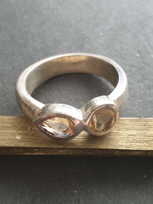 A siver ring with pink stons one rond and one teardrop the ring is stamp 925
