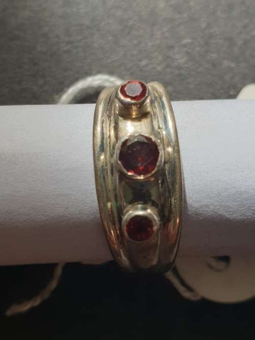 A sliver ring with 3 red stones rowed cut stone stamped 925