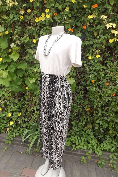 Jumpsuit in black and cream vertically striped in geometric pattern.Size 37/13.Zip at back