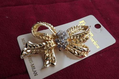 Glamorous gold toned bow with imitation diamonds.This brooch will dolly up any outfit.