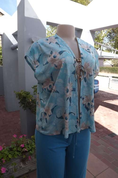 Short open sleeveless jacket in turquoise and beige floral pattern.Size 40/16.In good condition.