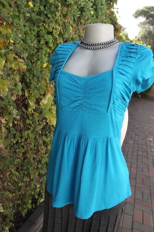 Turquoise/blue capped sleeve top in stretch polyester.Size 36/12.Tucked seam decoration on front