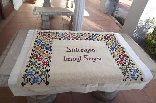 Beige vintage cross stitch embroidered wall decor with crochet rings at top.88 x 70cm.