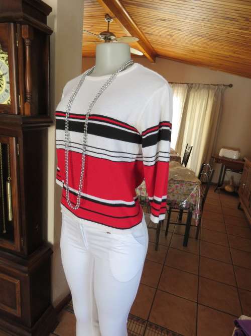 'TOPICS' white knitted top with black/red horizontal colour lines in size 34/10.In good condition.