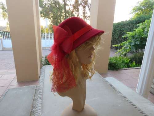 Red dolby style hat with ribbon,bow,feathers and netting.Good condition.