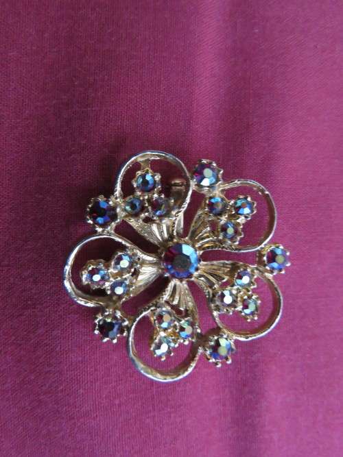 Smart round floral design gold toned brooch with blue/green shiny stones.New.