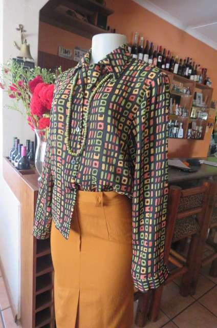 Beautiful black long sleeve polyester top with small green and peach graphic designs size 34/10.