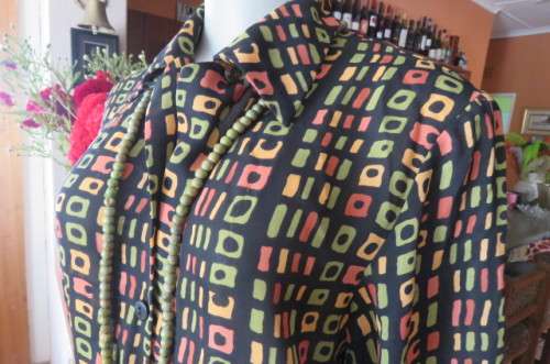 Beautiful black long sleeve polyester top with small green and peach graphic designs size 34/10.