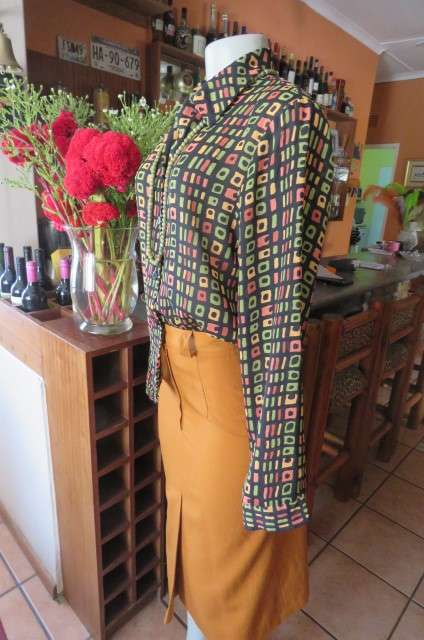 Beautiful black long sleeve polyester top with small green and peach graphic designs size 34/10.