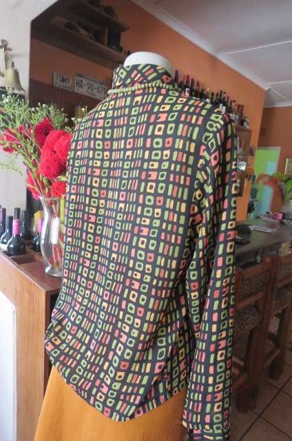 Beautiful black long sleeve polyester top with small green and peach graphic designs size 34/10.