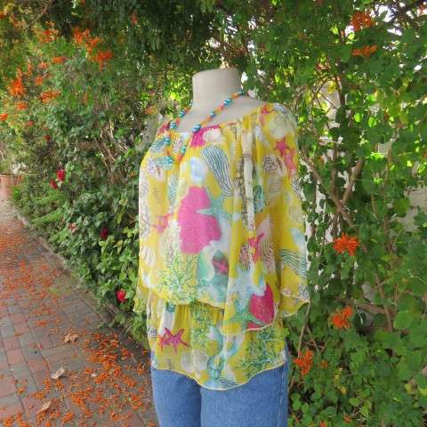 Sheer polyester peplum style top in yellow with pink and green shell designs. Size 38/14.