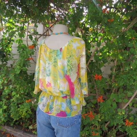 Sheer polyester peplum style top in yellow with pink and green shell designs. Size 38/14.