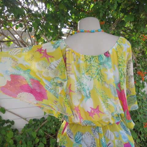 Sheer polyester peplum style top in yellow with pink and green shell designs. Size 38/14.