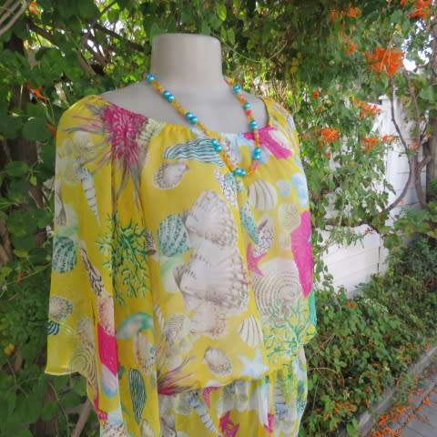 Sheer polyester peplum style top in yellow with pink and green shell designs. Size 38/14.