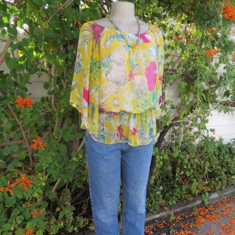 Sheer polyester peplum style top in yellow with pink and green shell designs. Size 38/14.