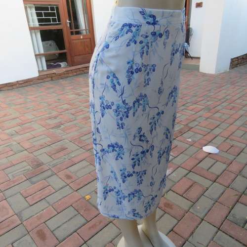 Pencil skirt in light blue with darker floral pattern. Size 32/8 by 'Sensations'. In 100% polyester.