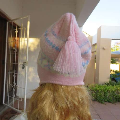 Cosy pink knitted earflap hat with ties. In blue, white pattern. Fleece inner. With pompom.