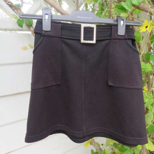 Little black ribbed polyester skirt. For girl 12 to 13 years old. Buckle on front. As new.