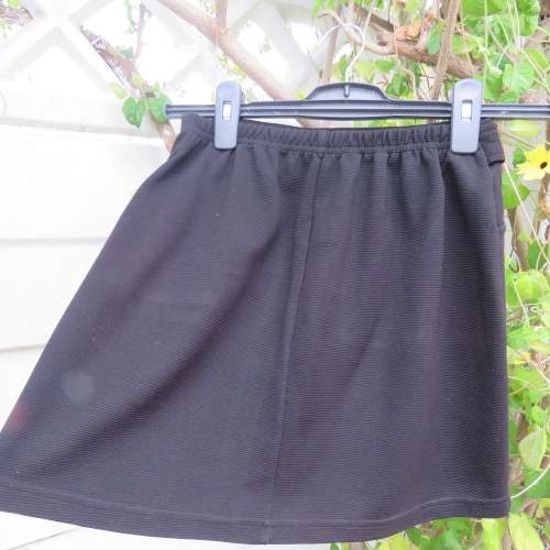 Little black ribbed polyester skirt. For girl 12 to 13 years old. Buckle on front. As new.