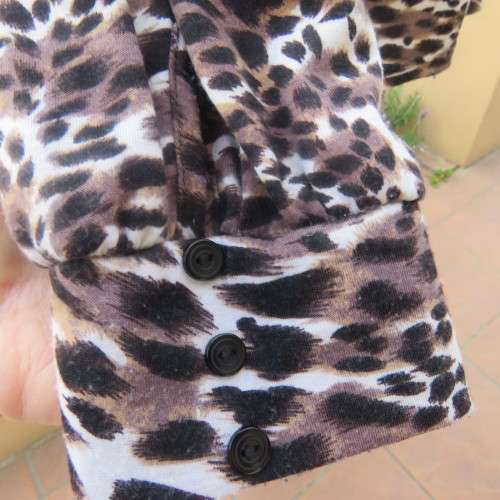 Soft and comfy polyester stretch top in animal print. Butt down with banded tie collar. Size 44/20