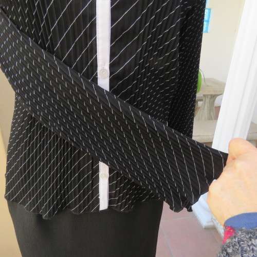 Elegant permanent pleated black top with thin diagonal stripes. Long sleeves. Size 38/14. As new.