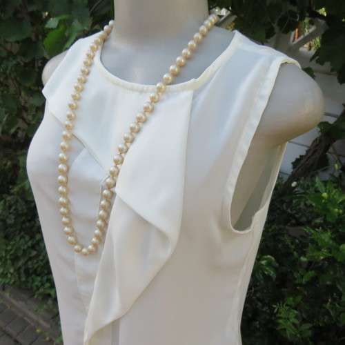 Unique cream sleeveless top with button down back. Size 34/10. By `Oakridge`. New condition.