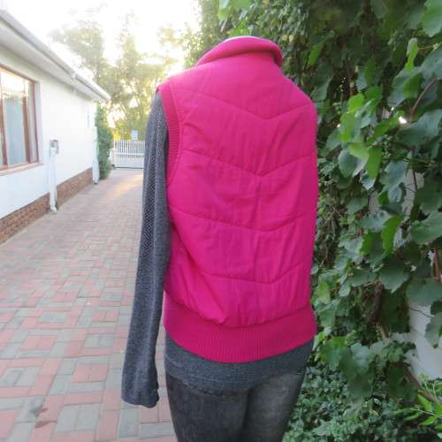 Warm magenta pink padded zip up waistcoat in size 36/12. Front pockets. Knitted ribbings.