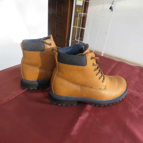 As new pair of tan colour size 4 boots for boys by (andUS). Laced up. Black inner and soles.