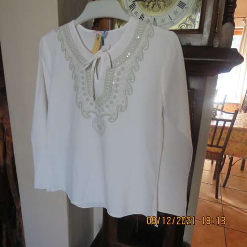 Pretty white slip over round neck top with front slit and tiestring.Patterned neckline.For 11/12 yr.