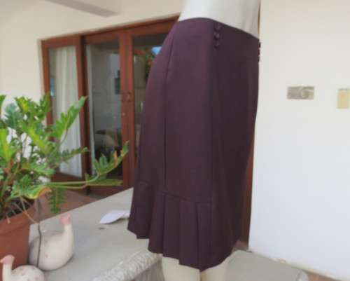 Elegant raisin colour medium length skirt.Bandless with zip at back.Pleats on bottom sides.Size 38