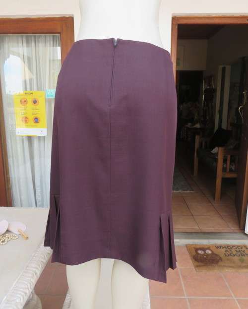 Elegant raisin colour medium length skirt.Bandless with zip at back.Pleats on bottom sides.Size 38