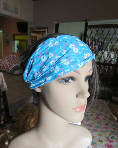 Skyblue folded polycotton hairband with white flowers and glitter.Elastic band at back.New condition