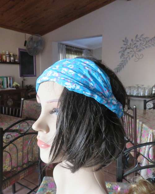 Skyblue folded polycotton hairband with white flowers and glitter.Elastic band at back.New condition