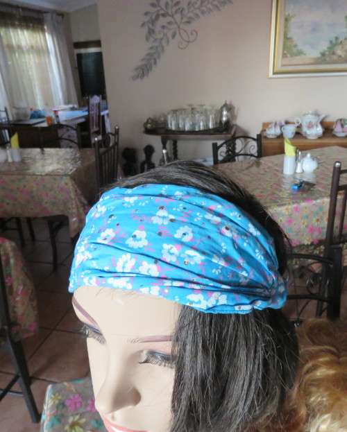 Skyblue folded polycotton hairband with white flowers and glitter.Elastic band at back.New condition