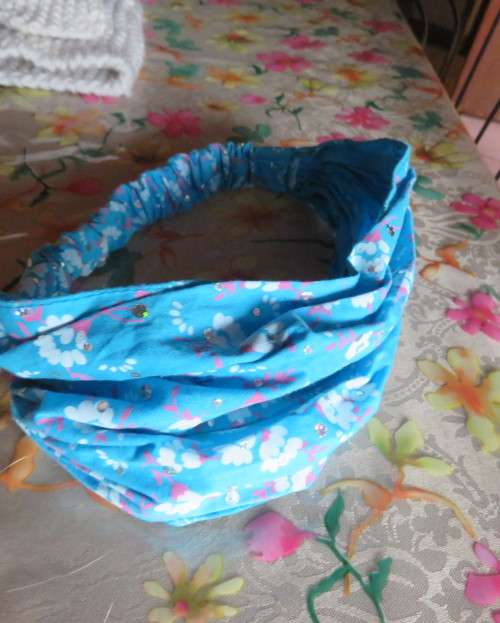 Skyblue folded polycotton hairband with white flowers and glitter.Elastic band at back.New condition