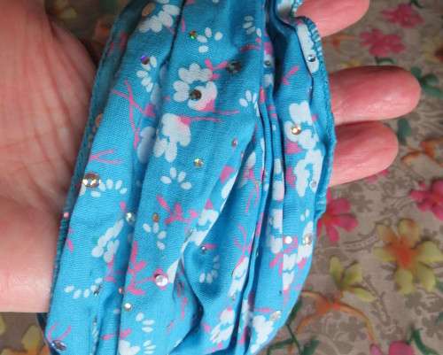 Skyblue folded polycotton hairband with white flowers and glitter.Elastic band at back.New condition