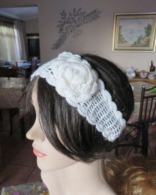 Delicate crochet acrylic stretch cream headband fasten with button at back and flower at side.