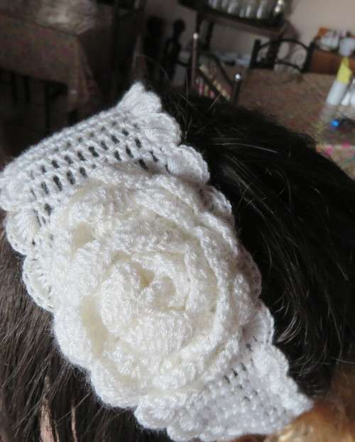 Delicate crochet acrylic stretch cream headband fasten with button at back and flower at side.