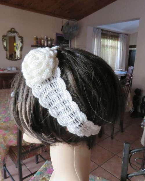 Delicate crochet acrylic stretch cream headband fasten with button at back and flower at side.