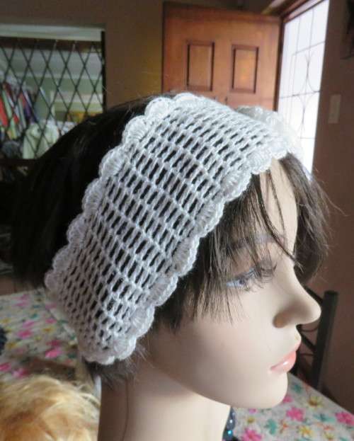 Delicate crochet acrylic stretch cream headband fasten with button at back and flower at side.