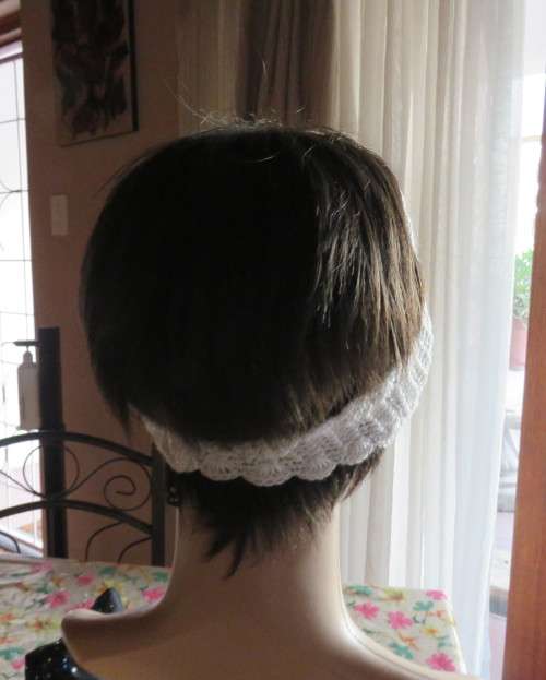Delicate crochet acrylic stretch cream headband fasten with button at back and flower at side.