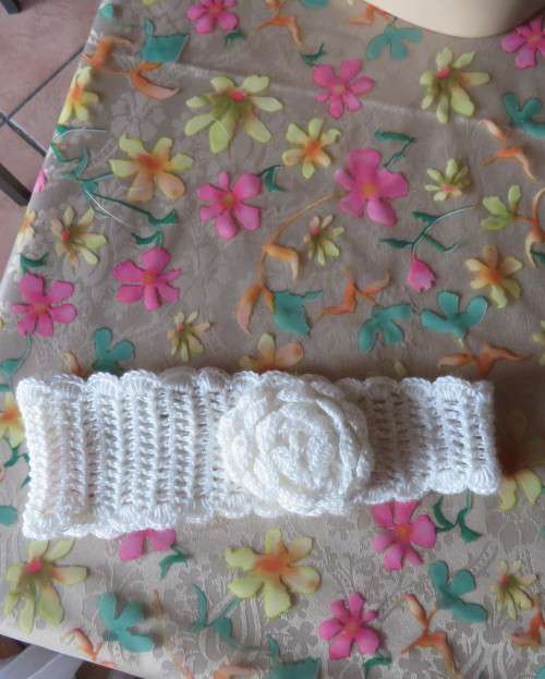 Delicate crochet acrylic stretch cream headband fasten with button at back and flower at side.