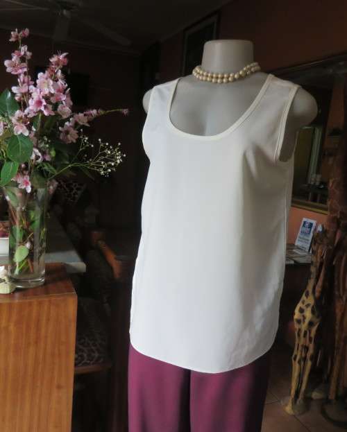 Cream cami style slip over silky polyester top by CONTRADICT size 36/12. Slits at sides.Scooped neck