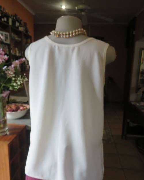 Cream cami style slip over silky polyester top by CONTRADICT size 36/12. Slits at sides.Scooped neck