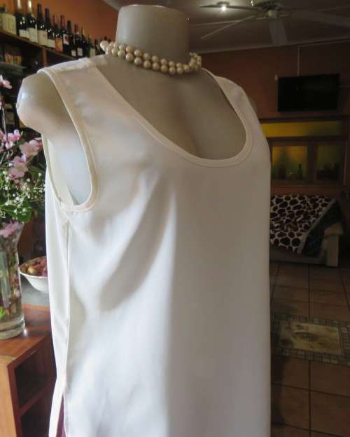 Cream cami style slip over silky polyester top by CONTRADICT size 36/12. Slits at sides.Scooped neck